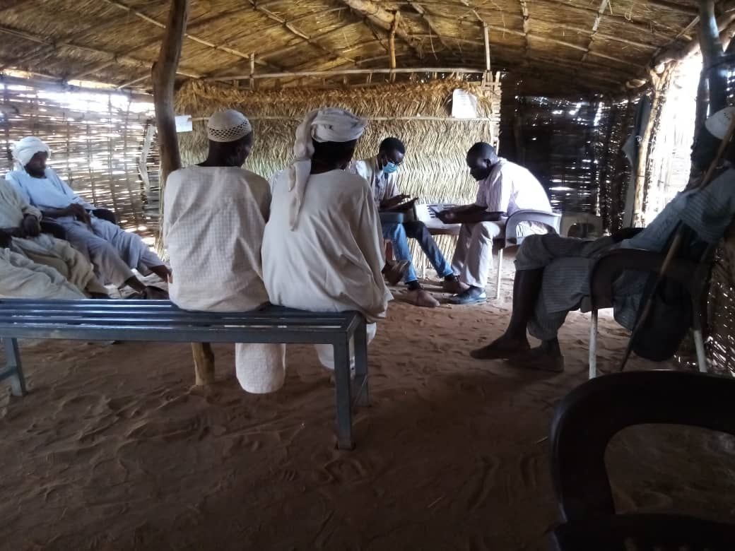 Image showing a group of locals sitting on benches in a house together in a discussion