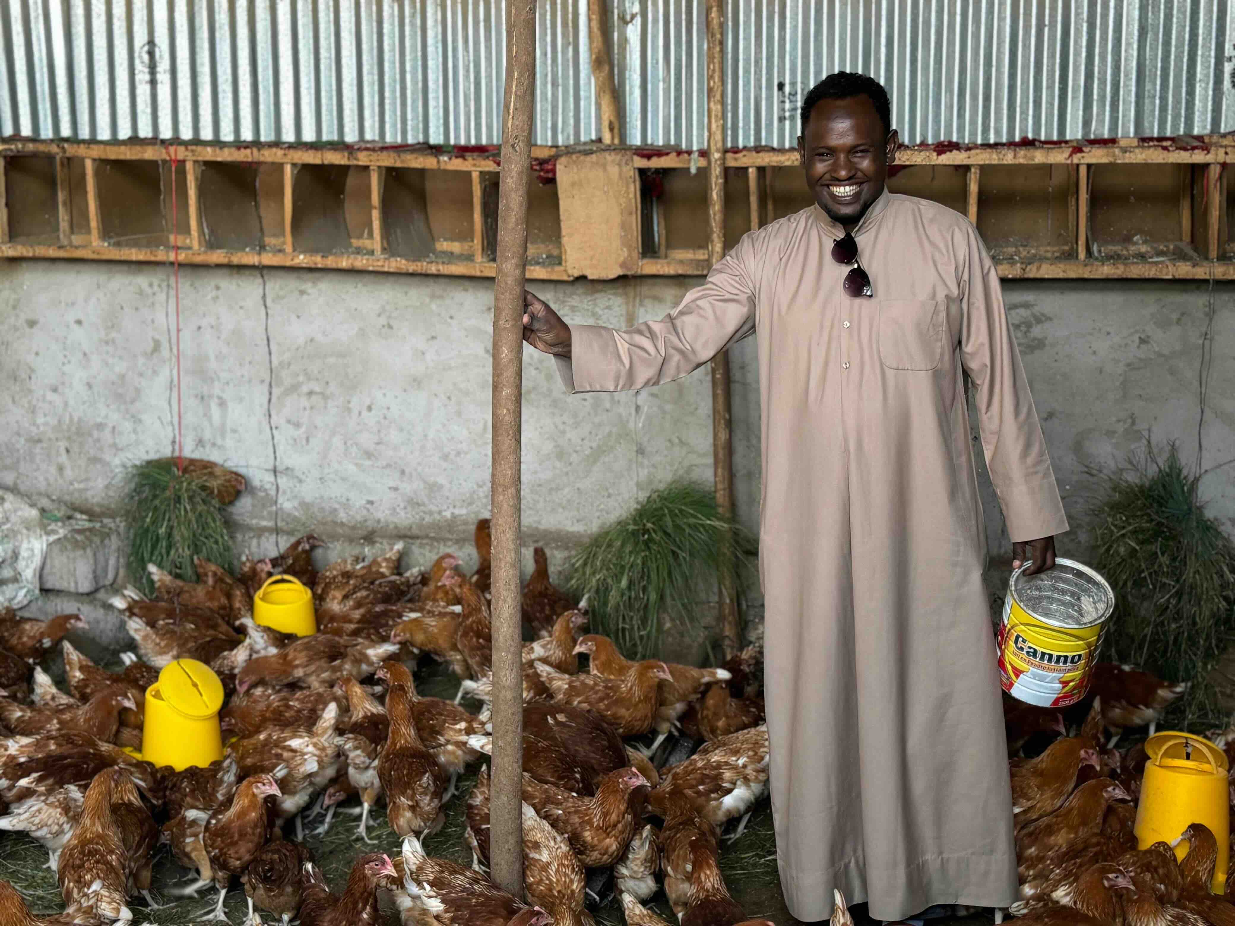 Image of a man smiling in a farm while feeding chicken